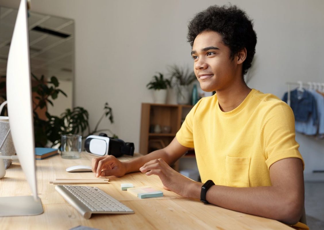 photo of boy wearing yellow shirt while using an imac